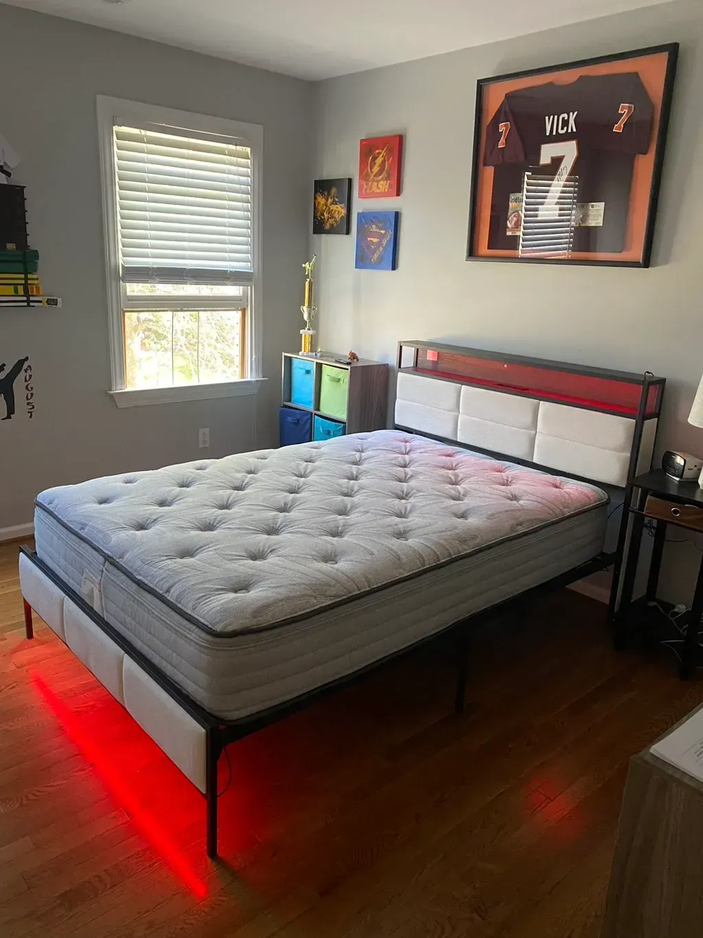 A bedroom with a bed and a picture of a football player on the wall.