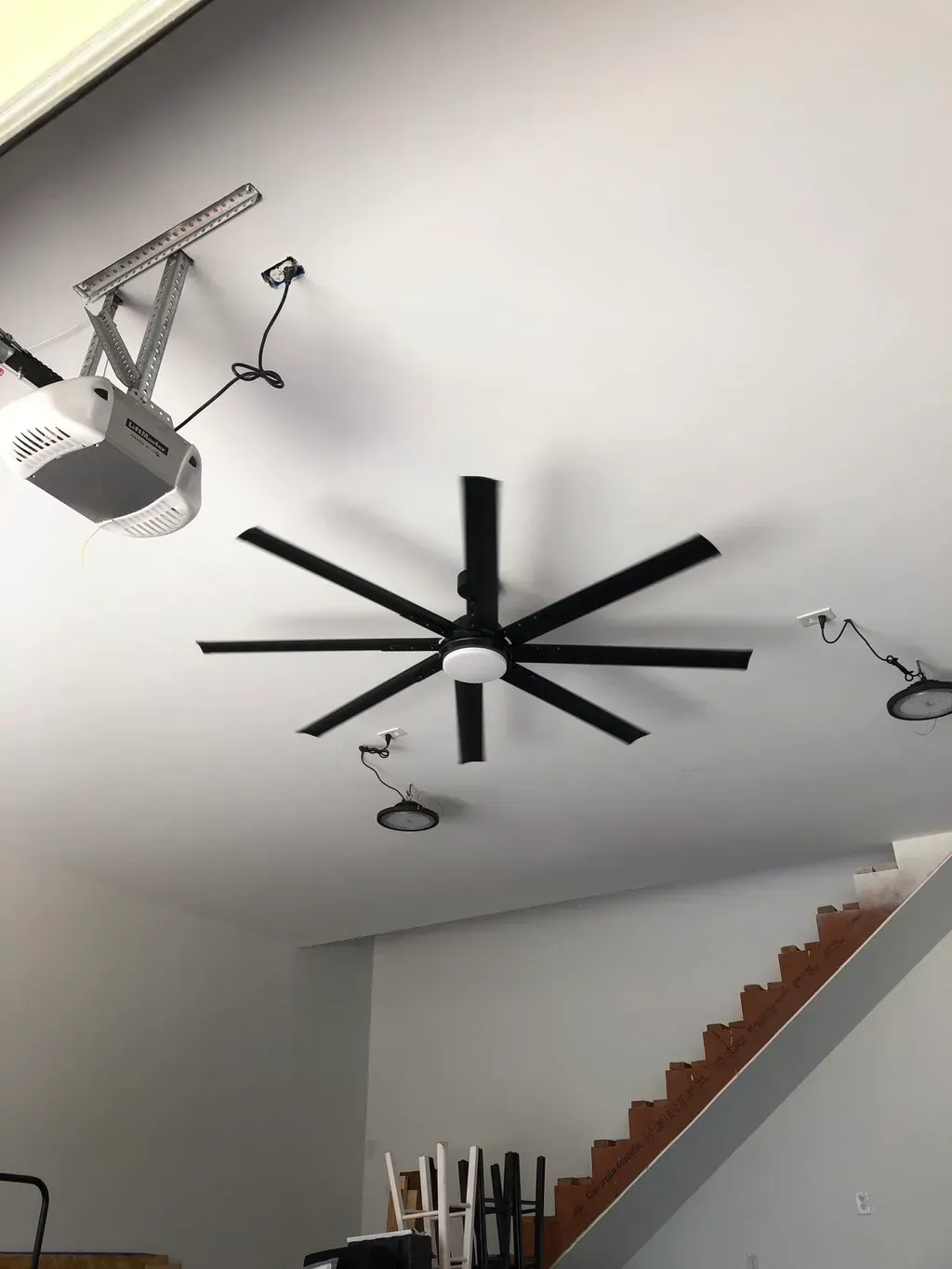 A ceiling fan is hanging from the ceiling above a garage door opener