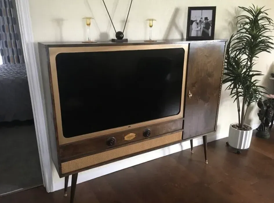 A large television is sitting on top of a wooden entertainment center in a living room.