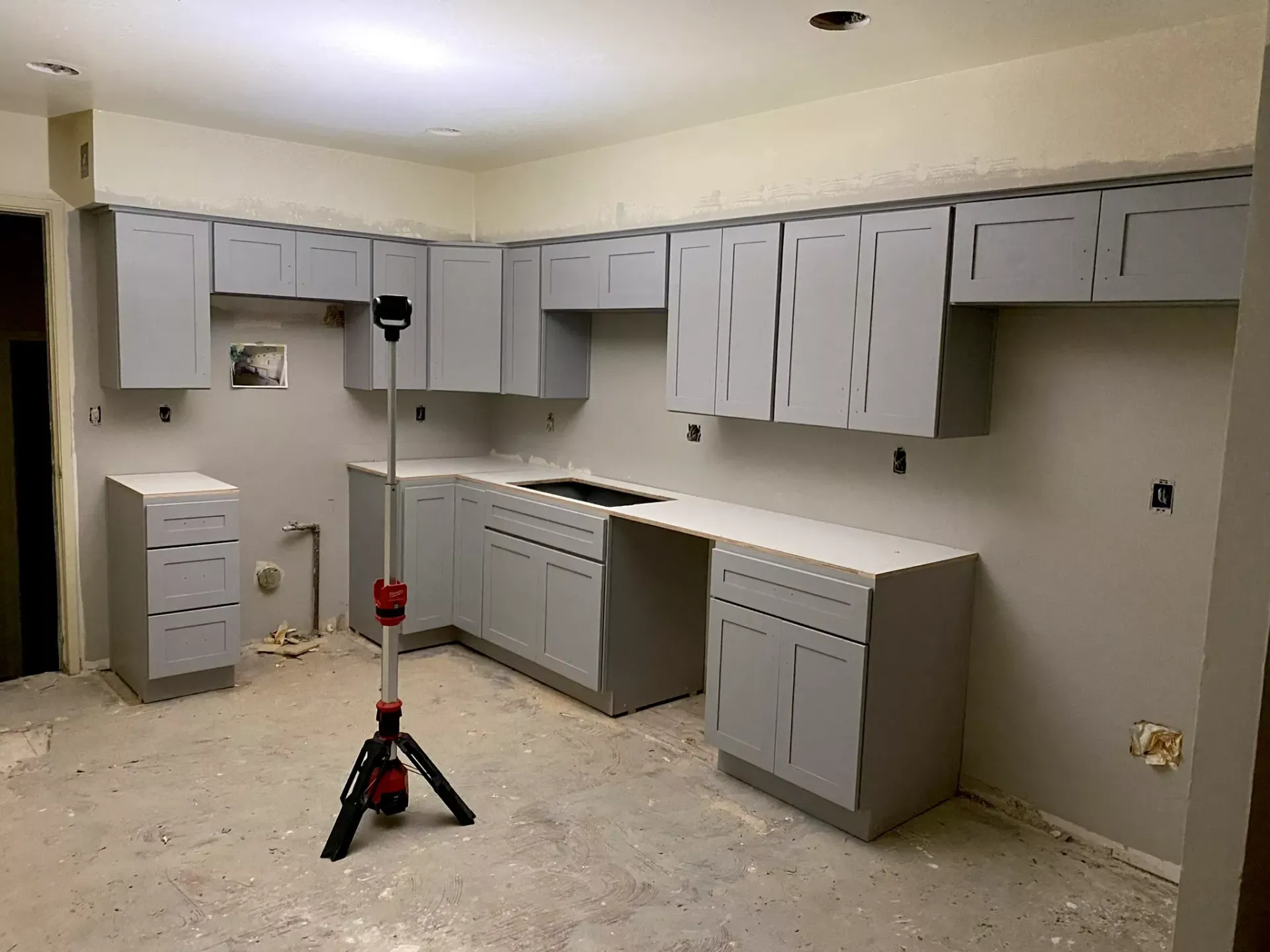 A kitchen with gray cabinets and a light on a tripod.