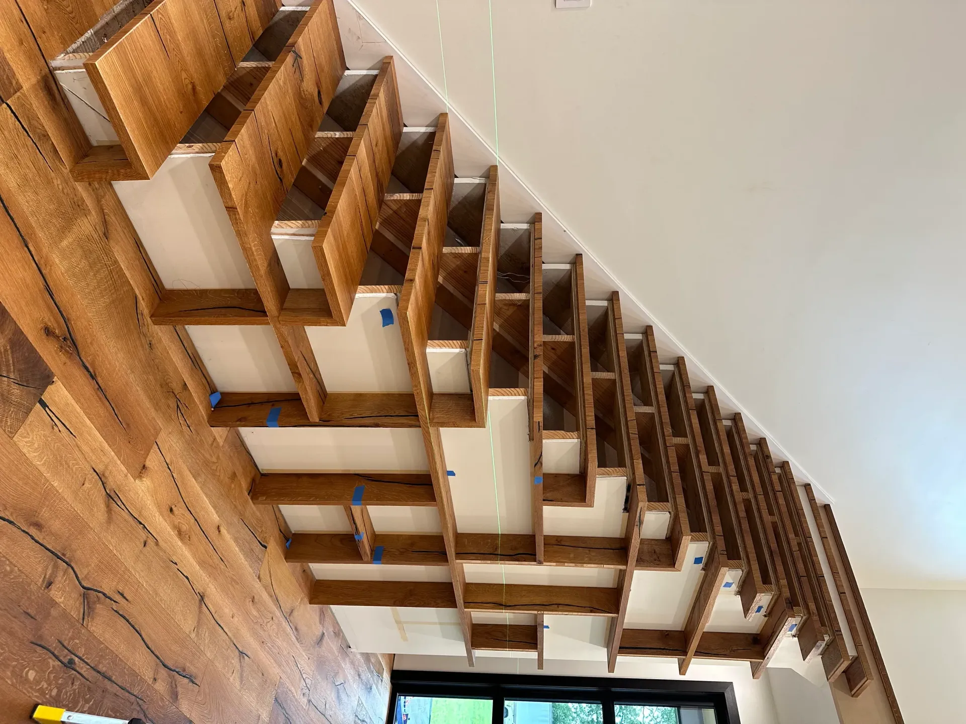A wooden staircase is being built in a house.