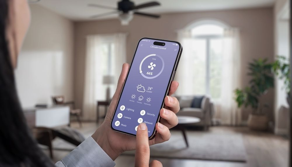 Hand holding a smartphone with a home control app open in a bright living room