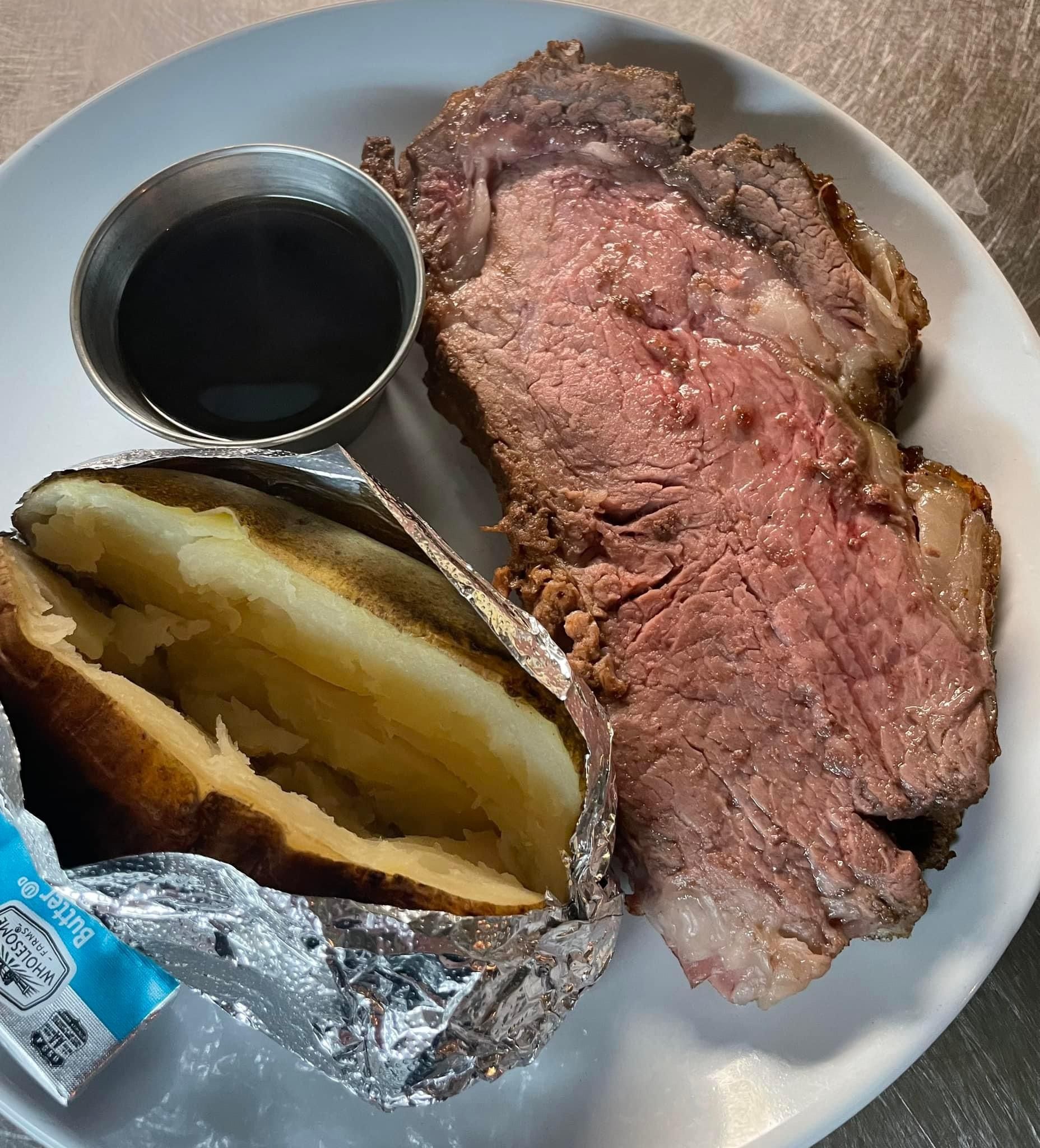A white plate topped with a steak and a baked potato