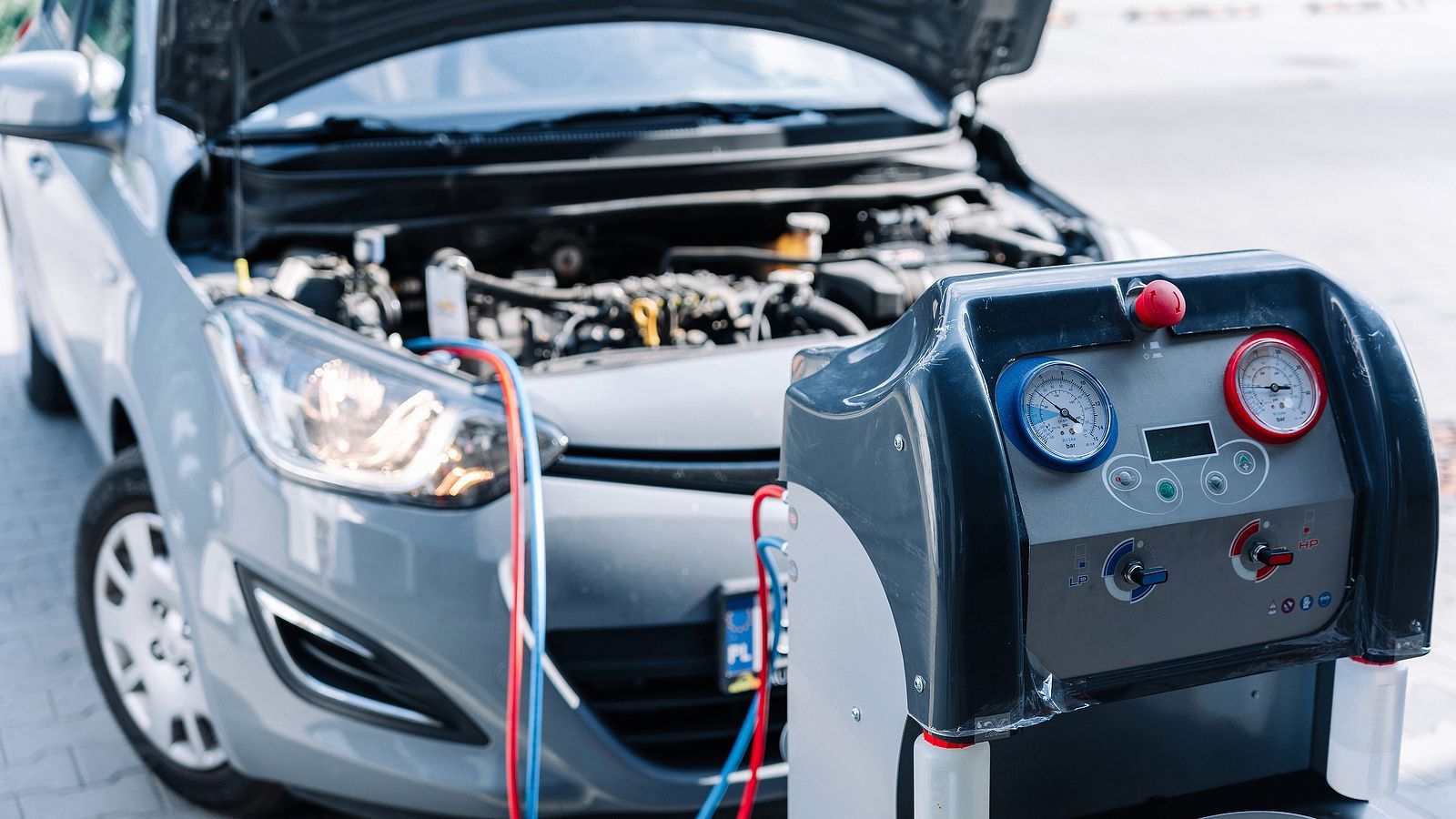 A car with the hood up is being serviced by a mechanic.