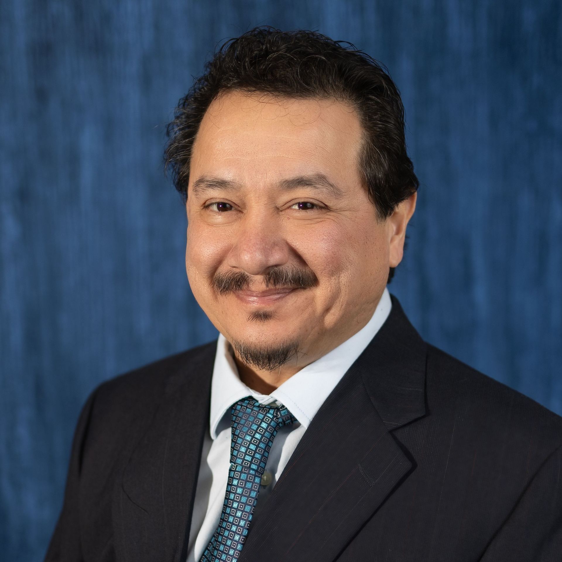 A man in a suit and tie is smiling for the camera.