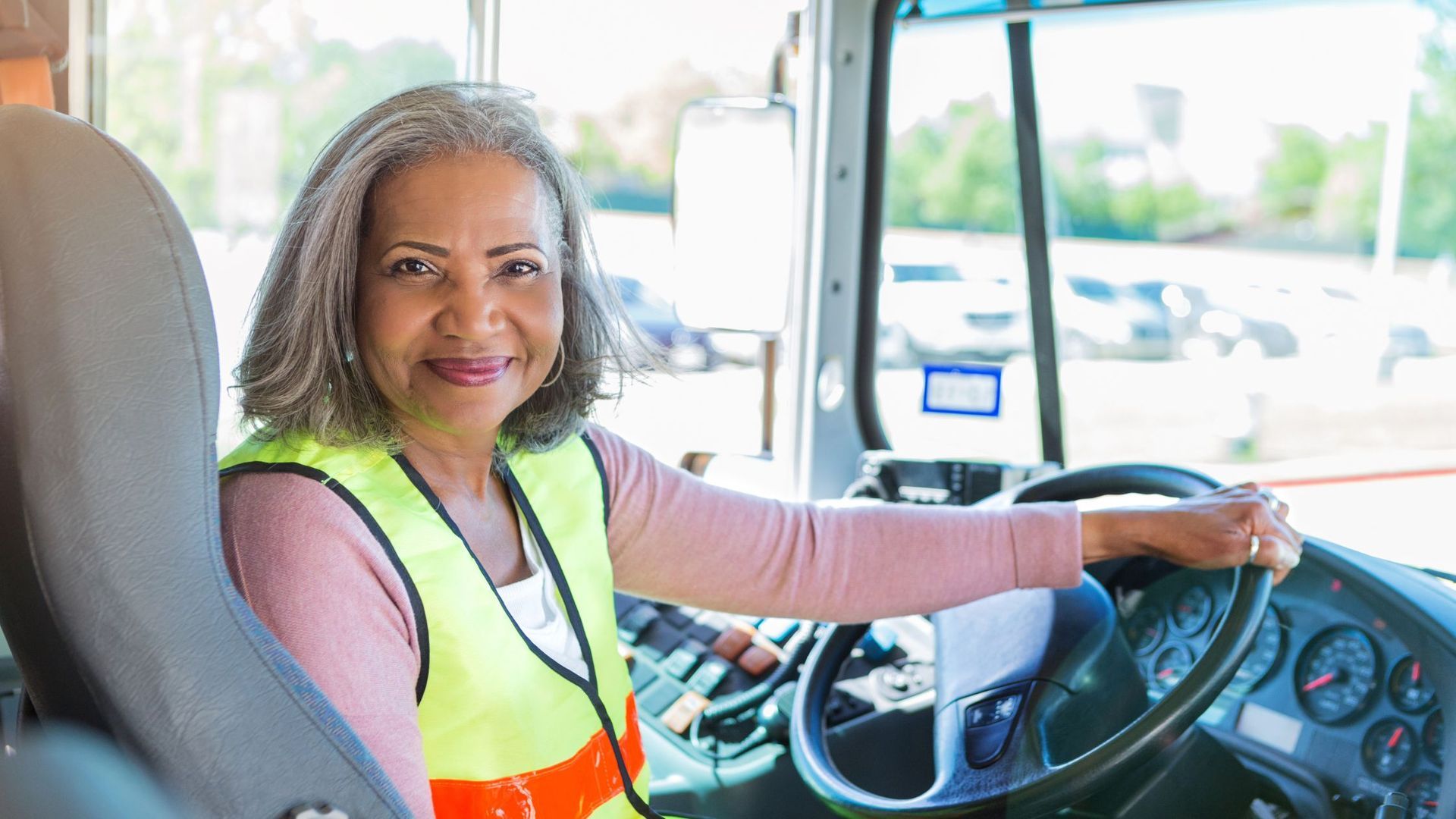 A woman is sitting in the driver's seat of a bus.