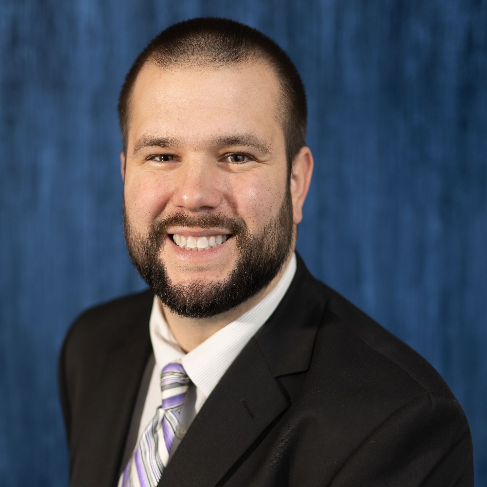 A man in a suit and tie is smiling for the camera