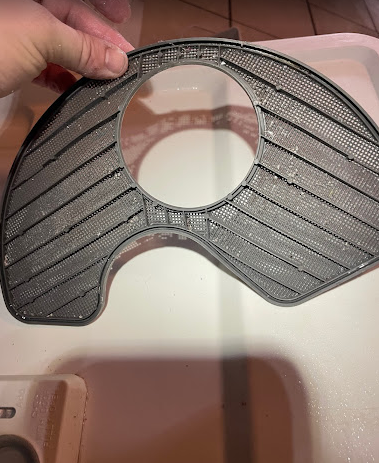 A person is holding a piece of plastic on top of a sink.