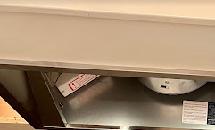 A stainless steel exhaust fan is hanging from the ceiling in a kitchen.