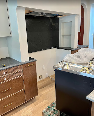 A kitchen with wooden cabinets and a black chalkboard.