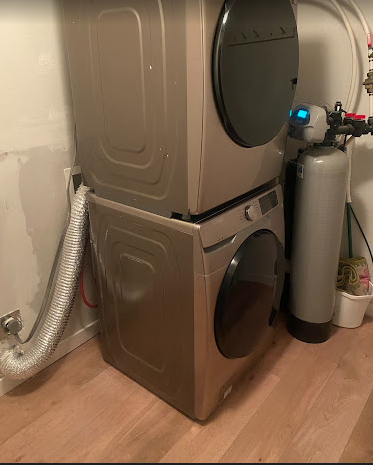 A washer and dryer are stacked on top of each other in a laundry room.