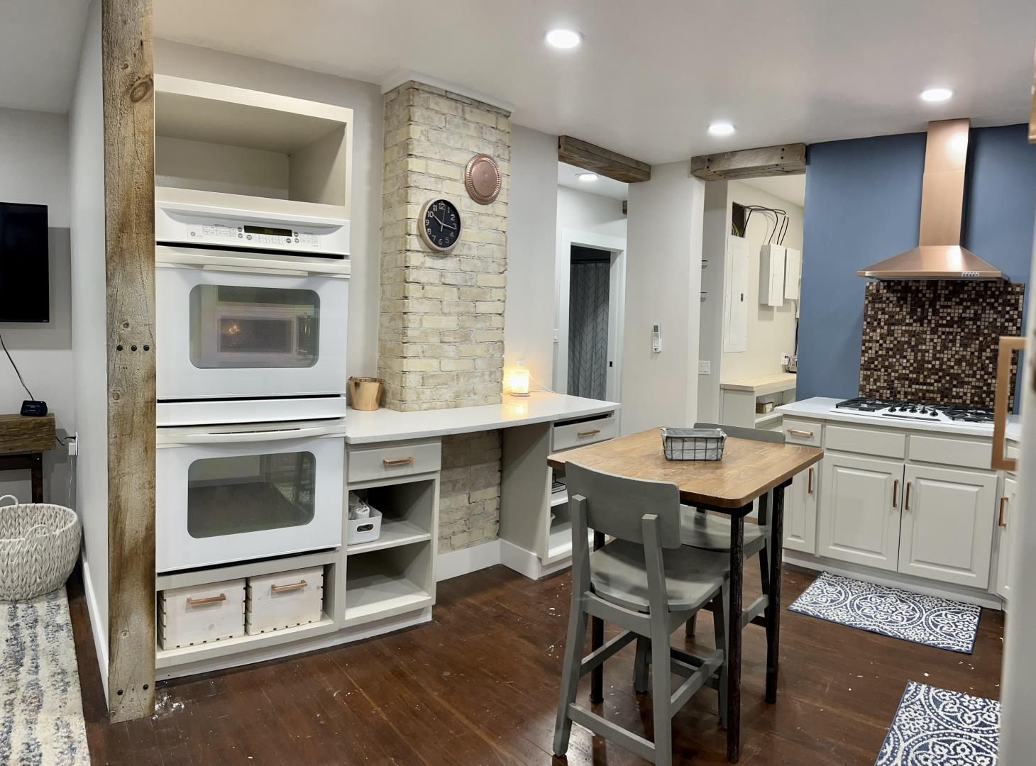 A kitchen with two ovens stacked on top of each other and a table.