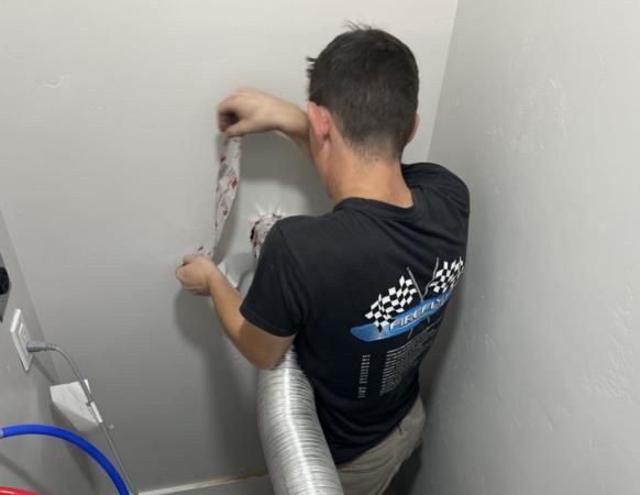 A man in a black shirt is working on a wall