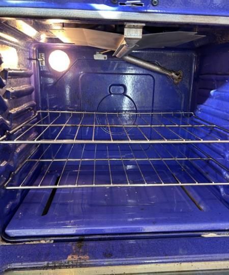 The inside of a blue oven with a light on