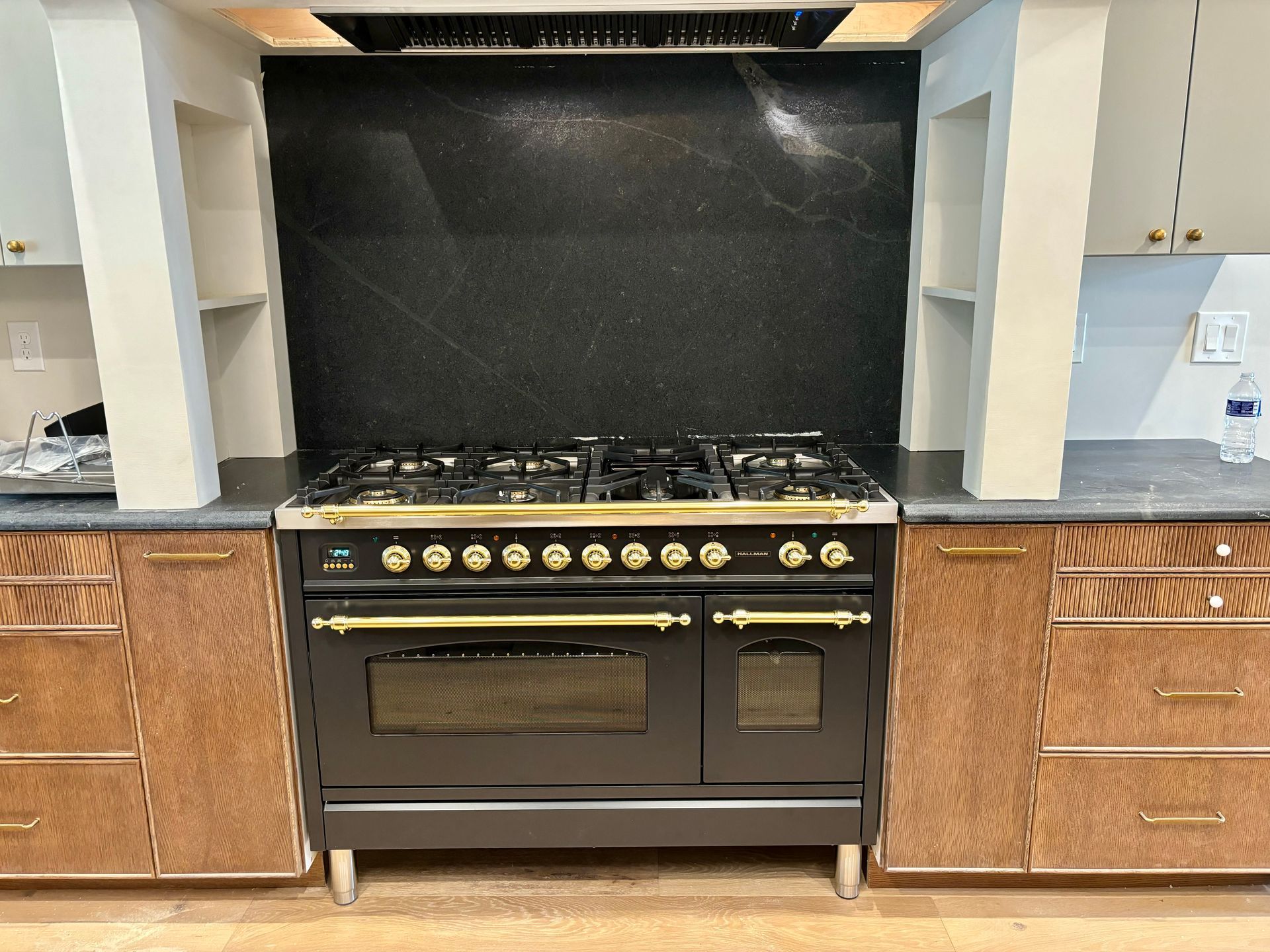 A black stove and oven in a kitchen with wooden cabinets