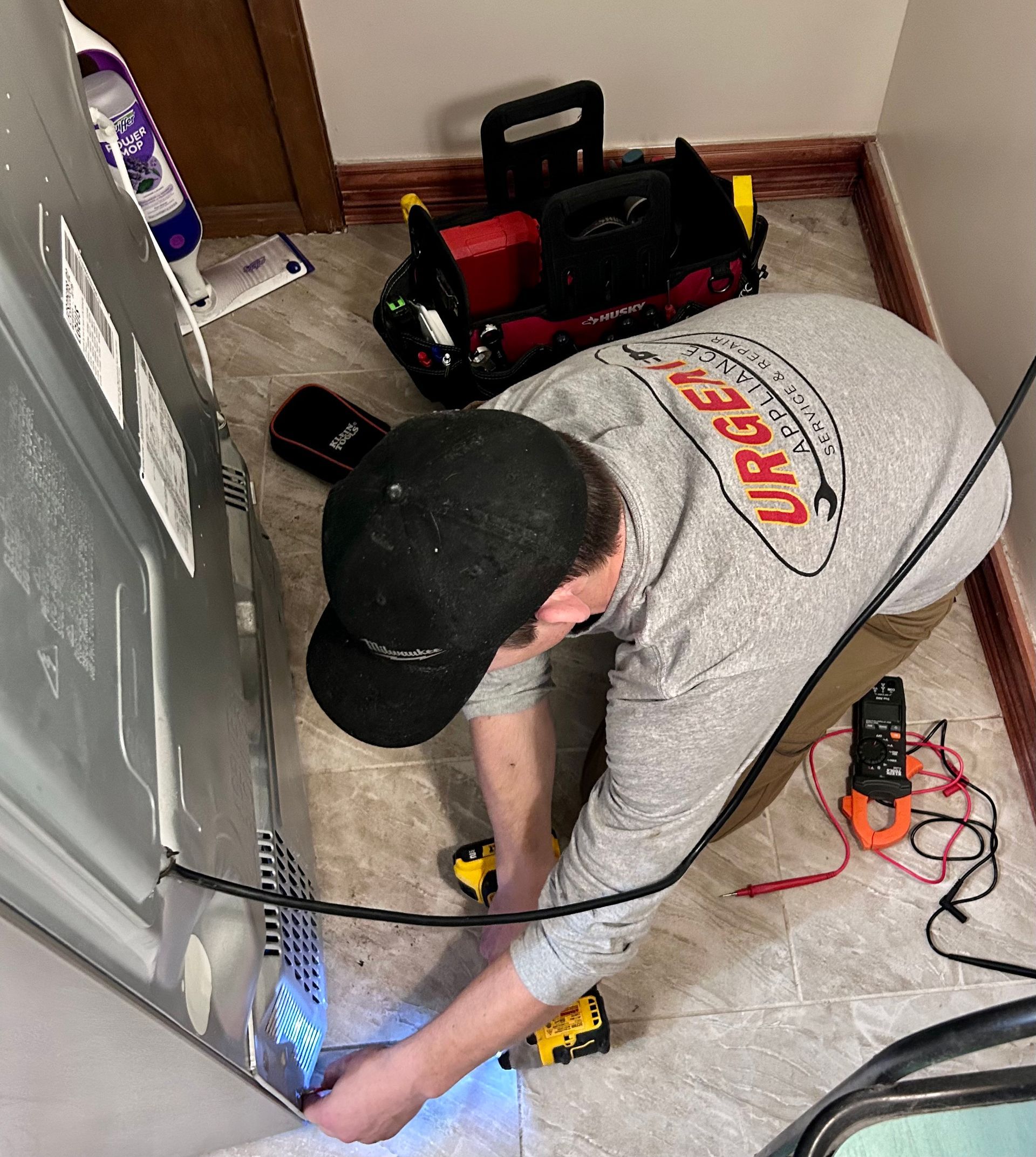 A man is working on a refrigerator in a room.