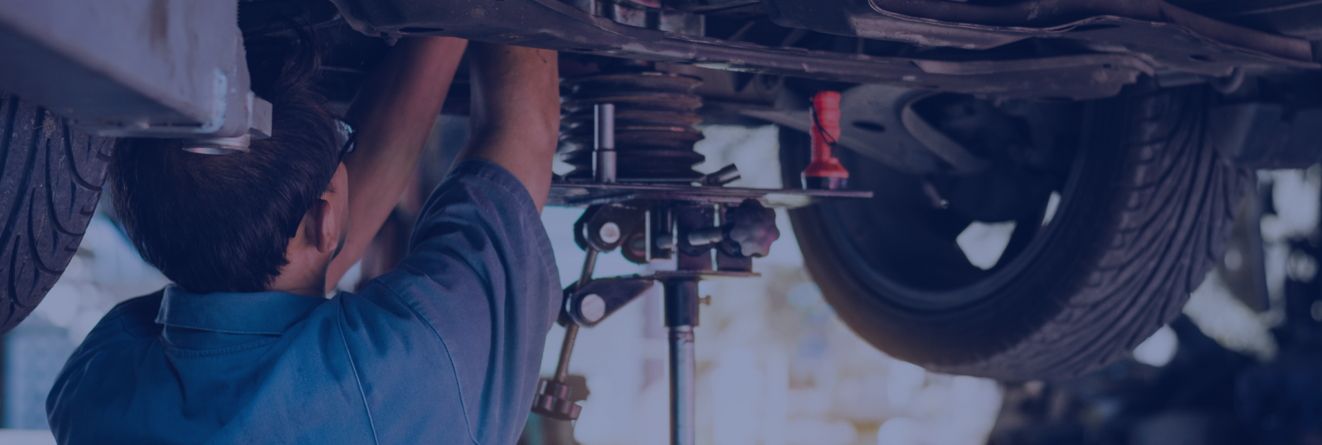 Mechanic working on the underside of a car, using tools. | Driver's Choice