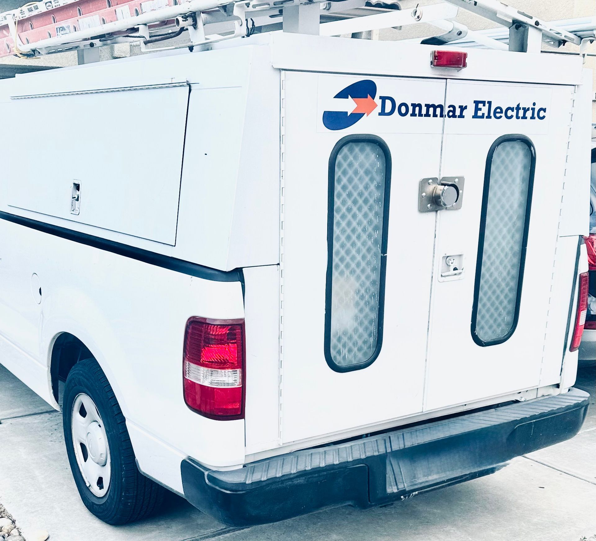 White Donmar Electric utility van, showing the rear doors and a roof ladder rack.