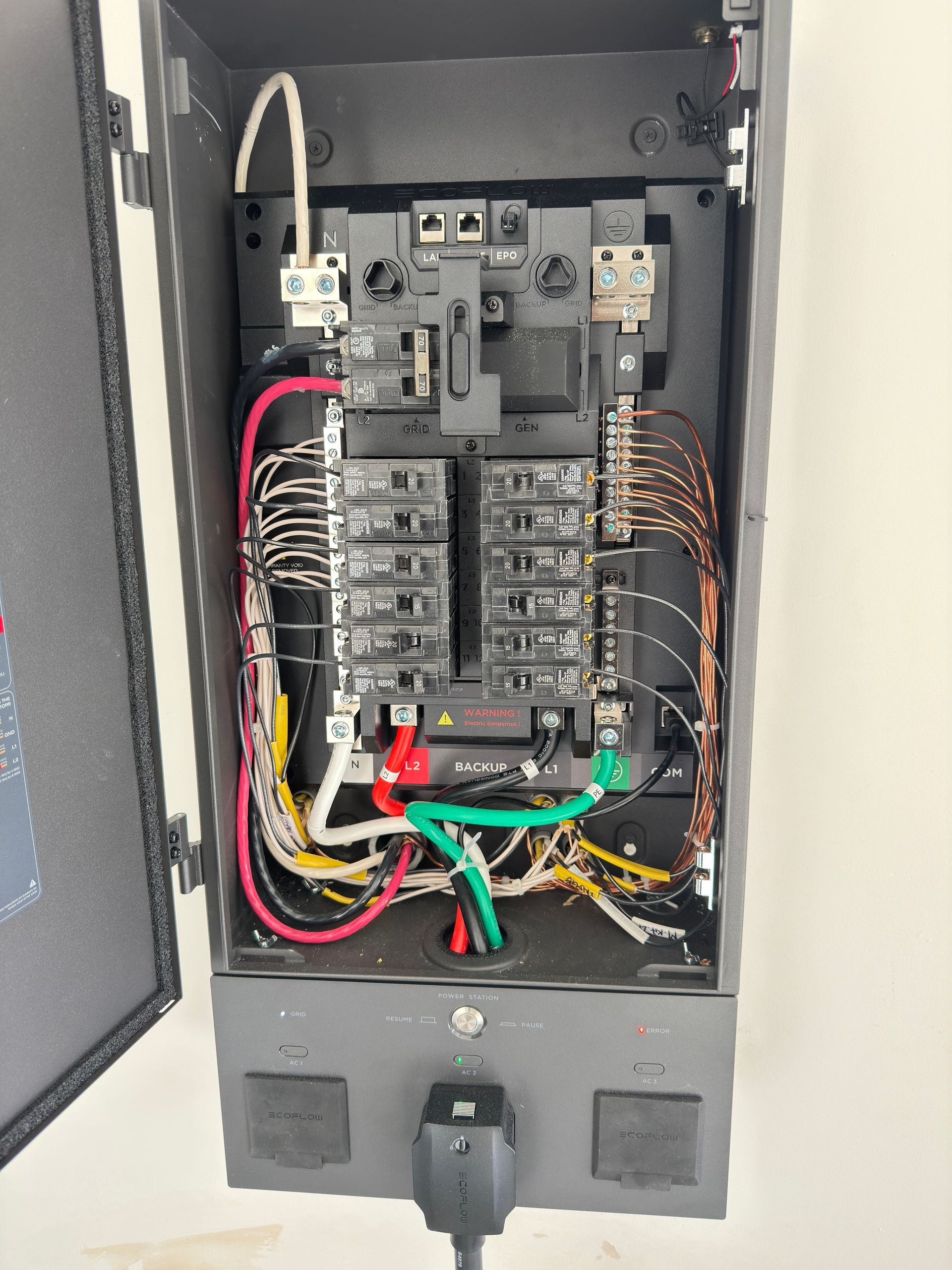 Open electrical service panel with a black exterior, internal circuit breakers, and colored wiring visible inside.