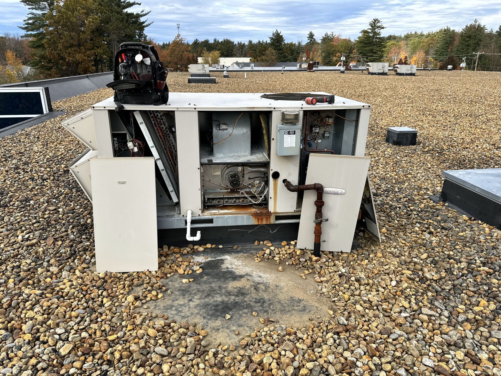 An air conditioner is sitting on top of a gravel covered roof.