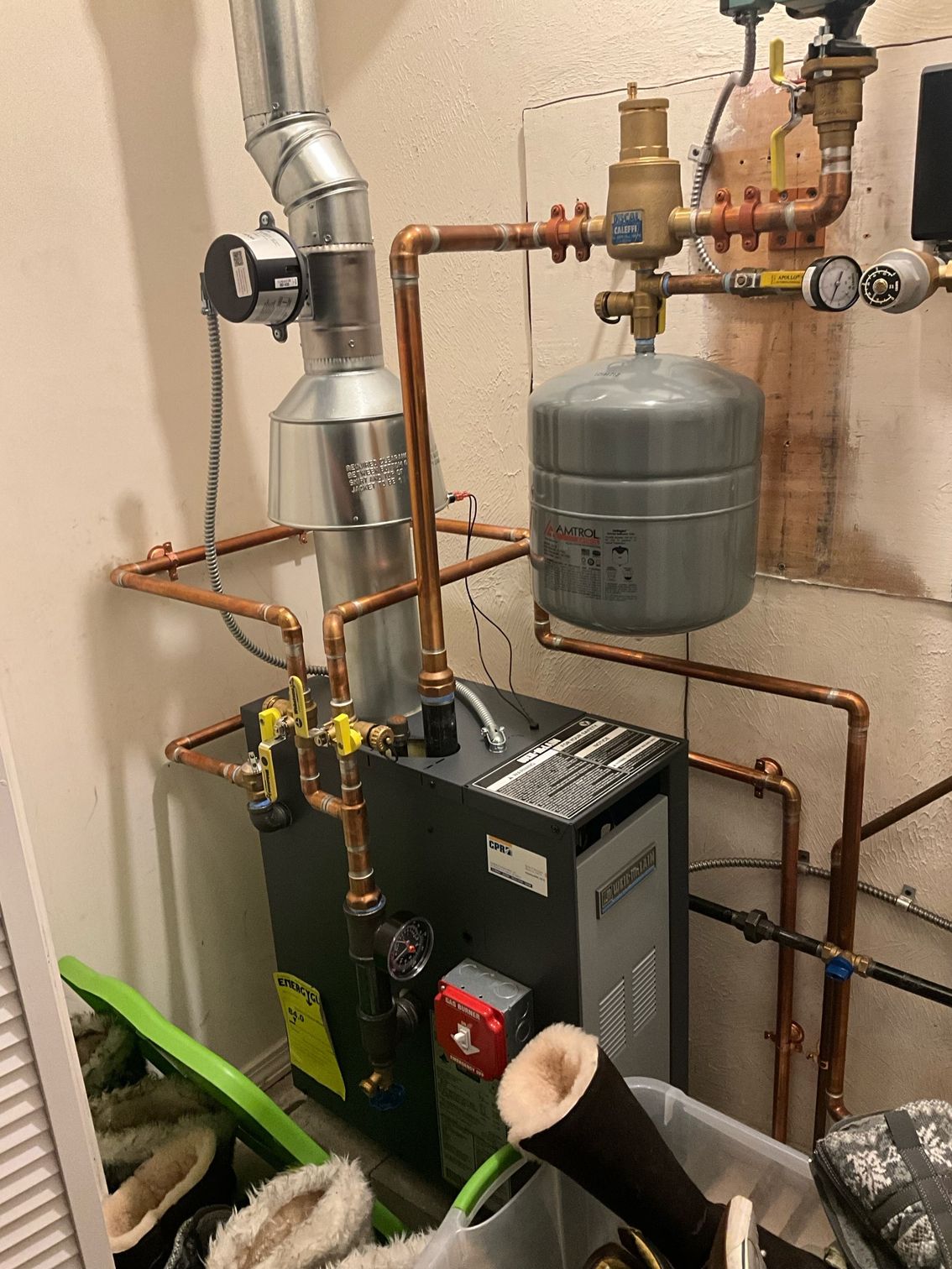 A water heater is sitting in a room with a lot of pipes.