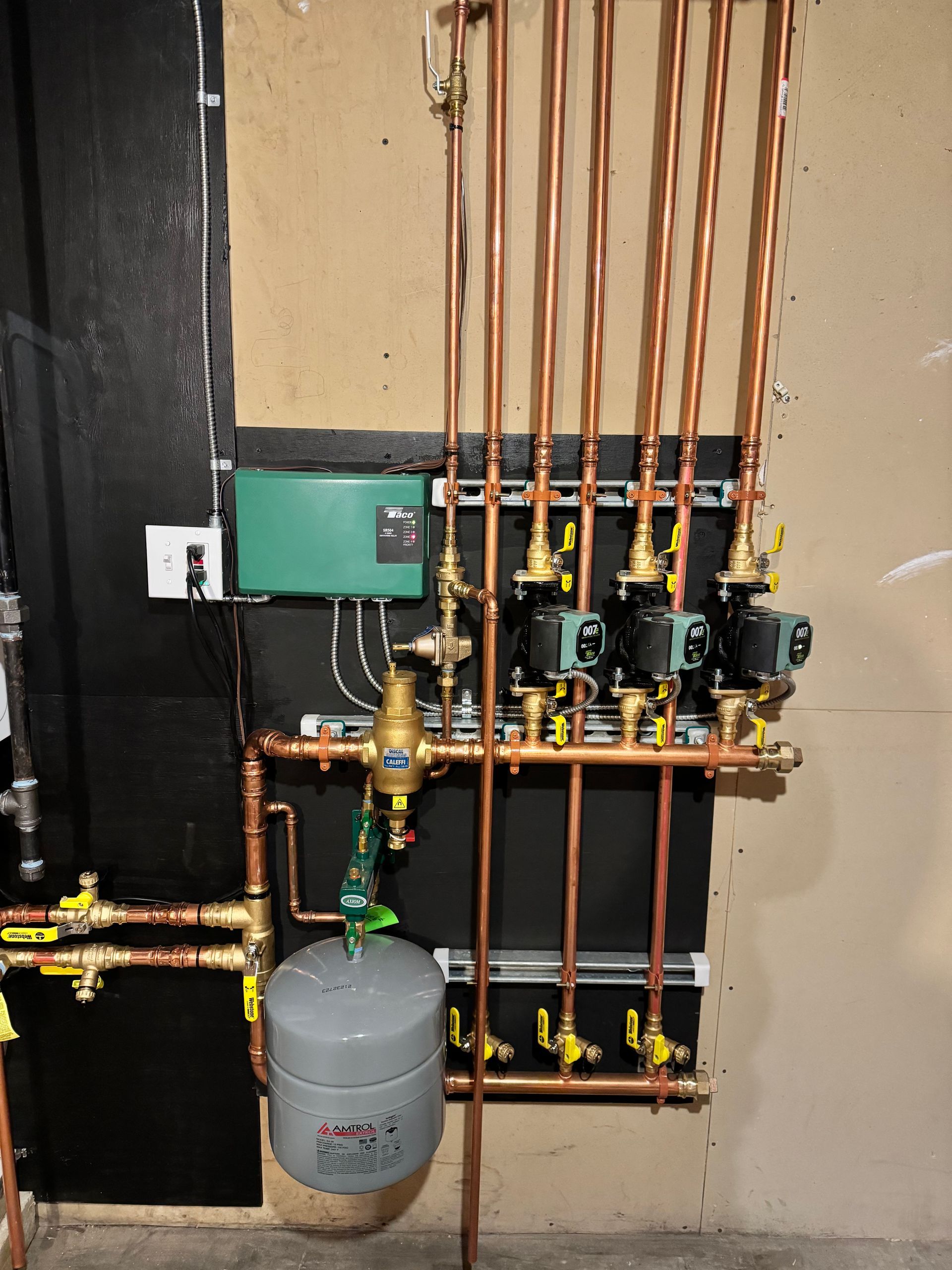 A wall with copper pipes and valves on it