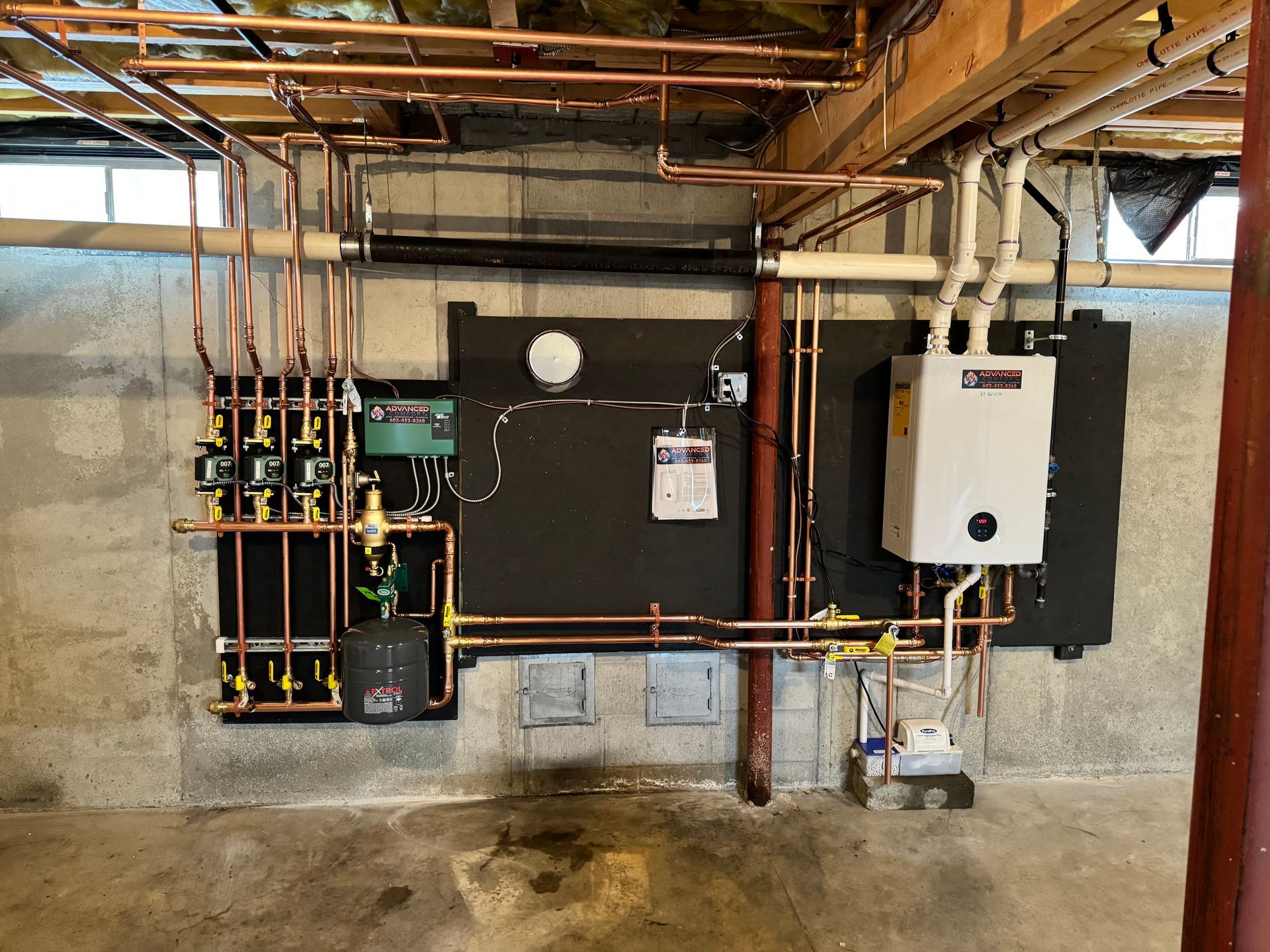 A basement with a lot of pipes and a boiler on the wall.