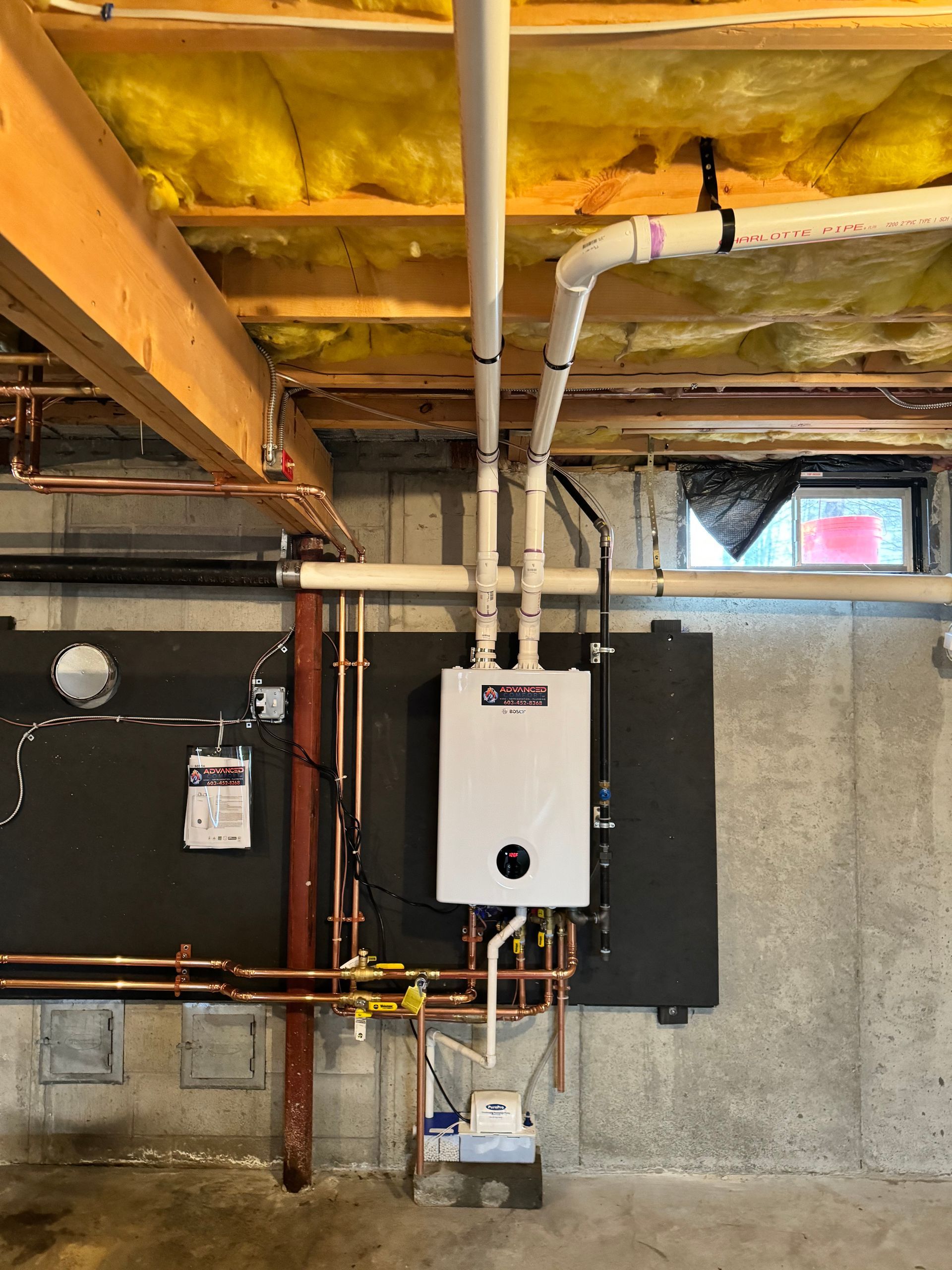 A water heater is hanging from the ceiling of a basement.