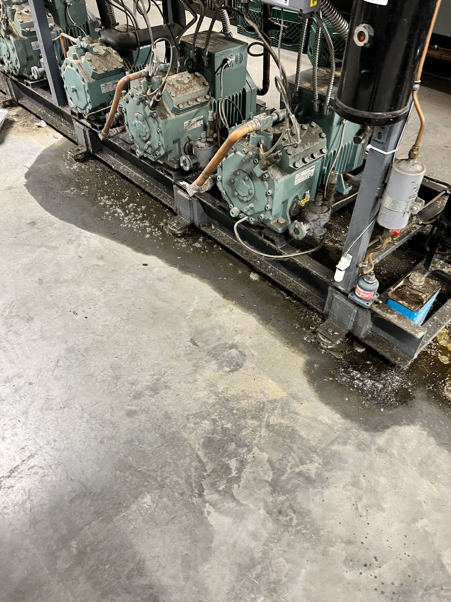 A row of compressors are sitting on a concrete floor in a warehouse.