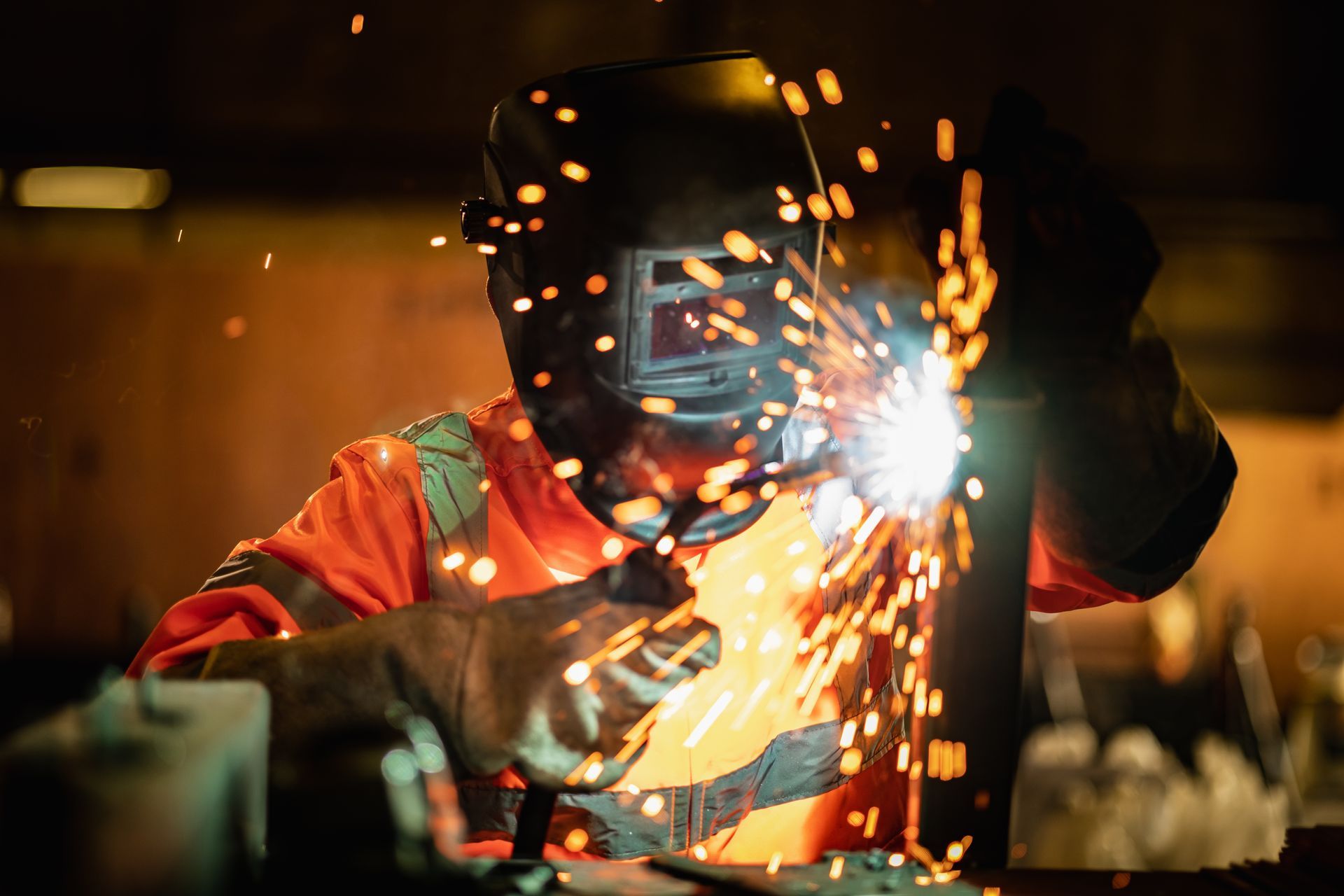 A man is welding a piece of metal in a factory.