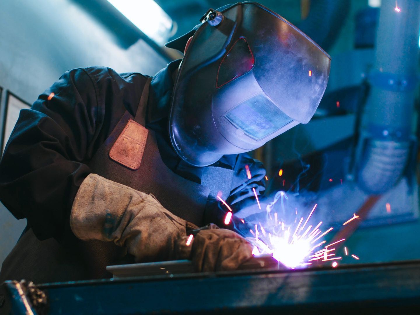 A man is welding a piece of metal in a factory.