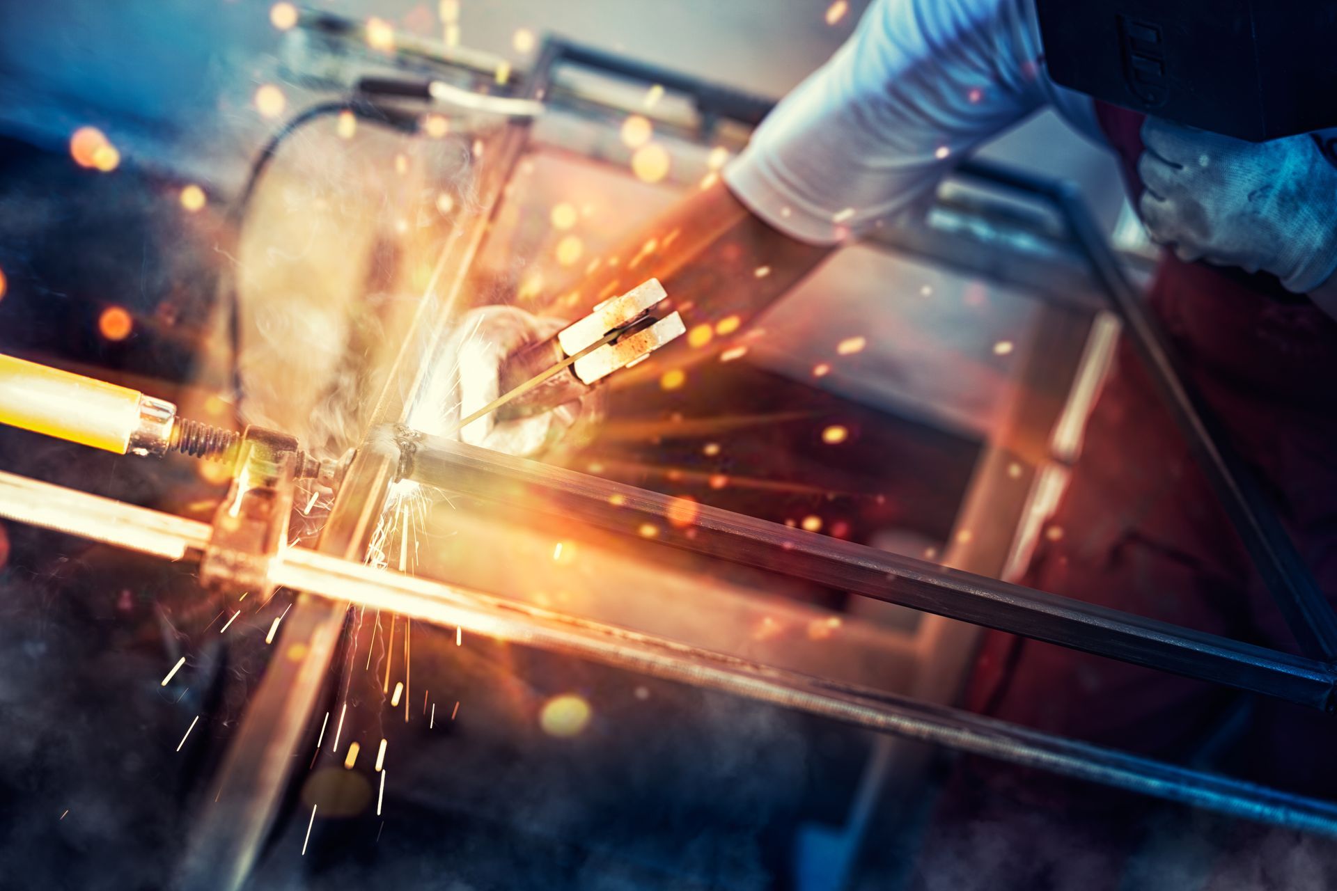A man is welding a piece of metal in a factory.