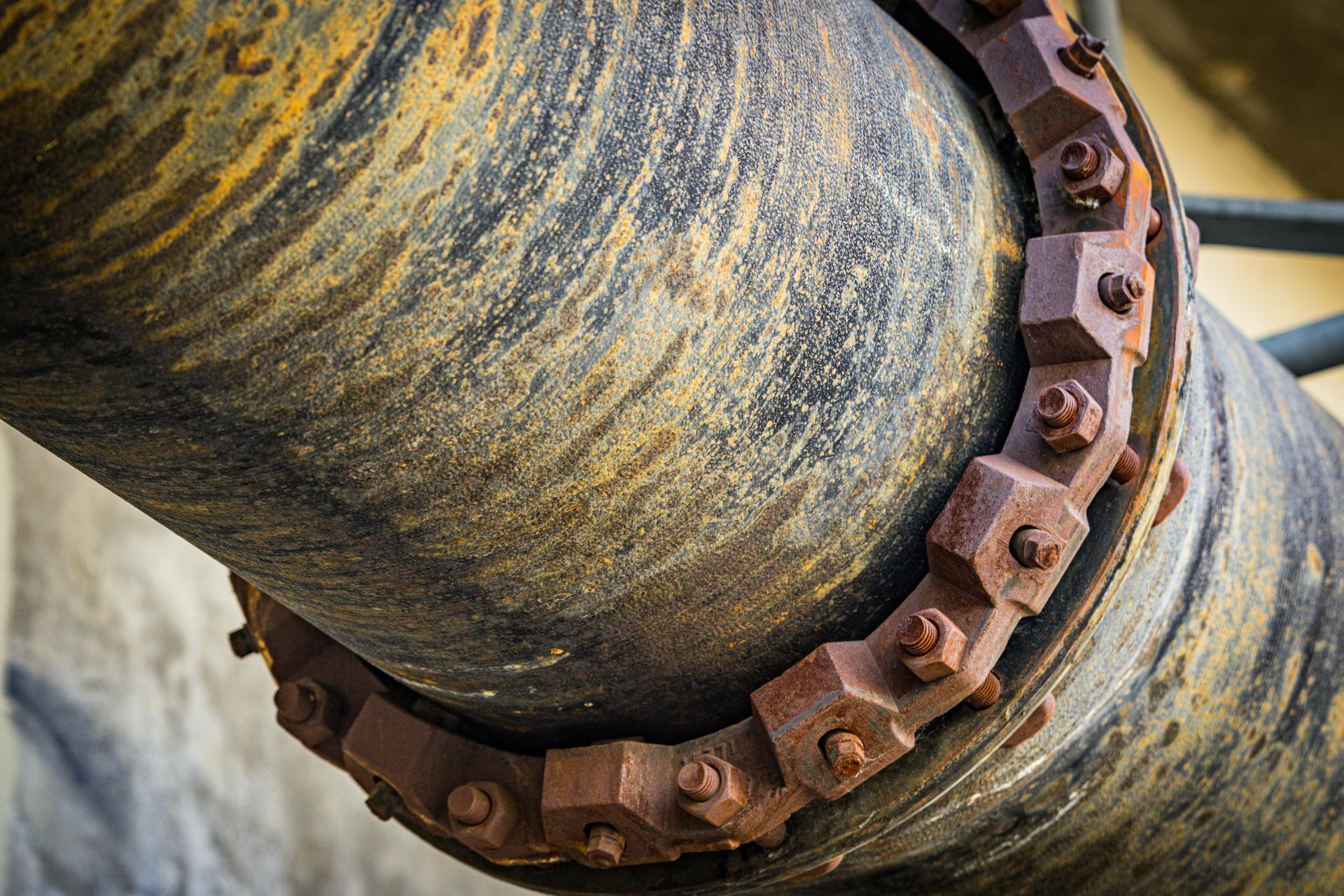 A close up of a rusty pipe with a chain around it.