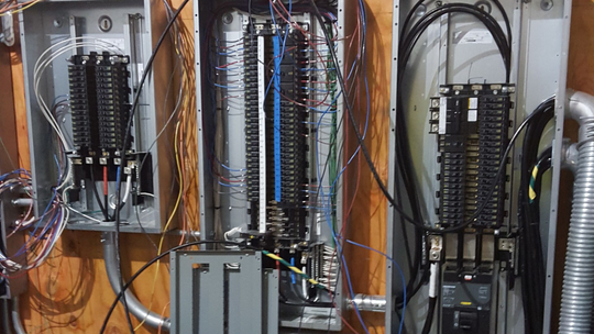 Electrical panels with numerous wires in a wall.