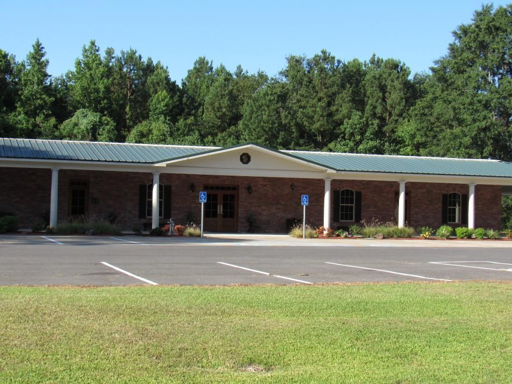 Brick building with green metal roof, accessible parking spaces, and lawn.