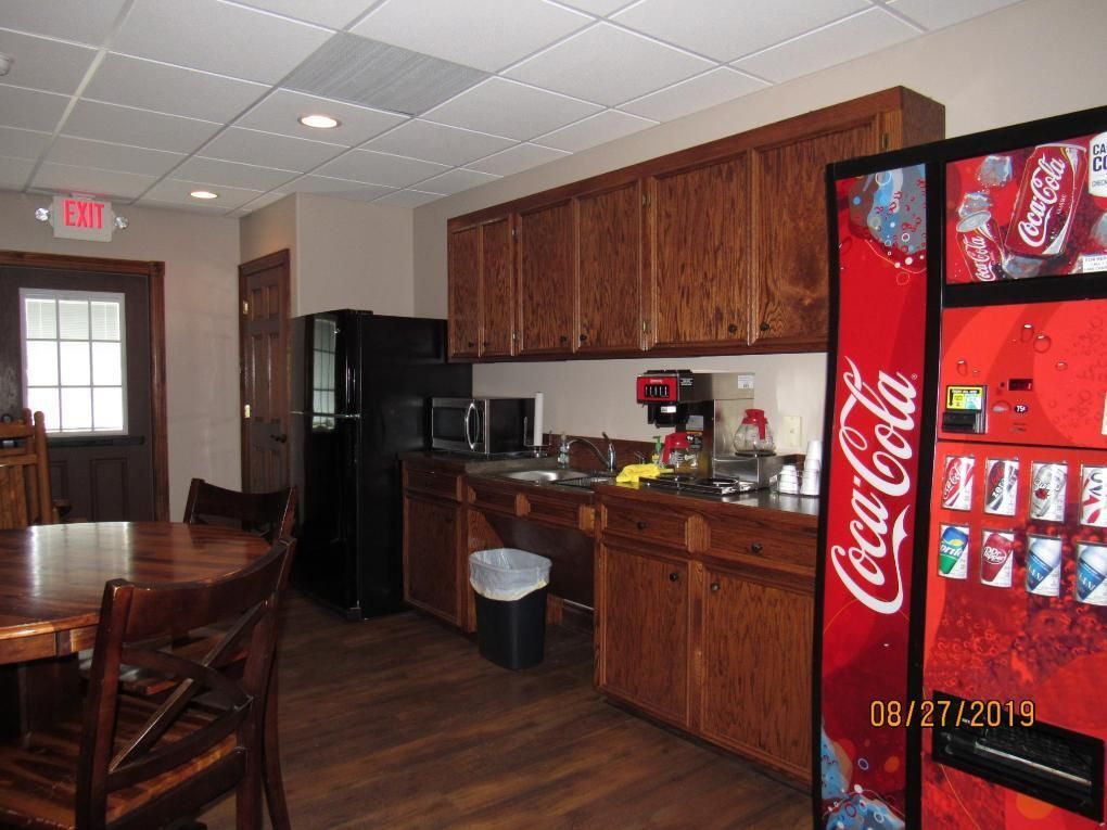 Break room with cabinets, appliances, soda machine, and a table.