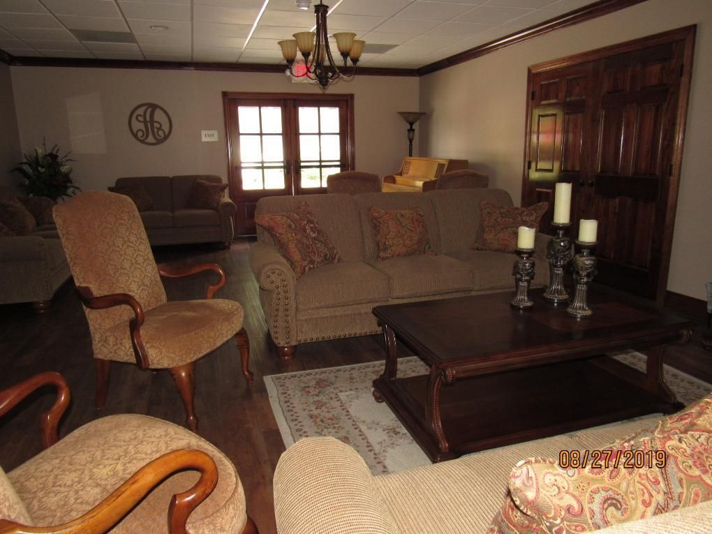 Living room with brown sofas, chairs, wooden door, and a coffee table with candles.