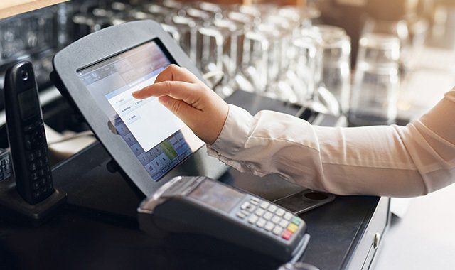 La mano di una persona che interagisce con un sistema touch screen per punti vendita al bancone, magari in un ristorante.