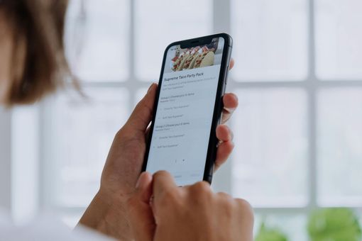 Persona con in mano uno smartphone che scorre una lista. Interno luminoso, luce naturale.