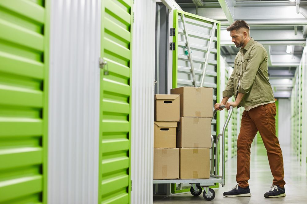A Man is Pushing a Cart Filled With Boxes in a Storage Unit — Dunford Removals in Qunaba, QLD