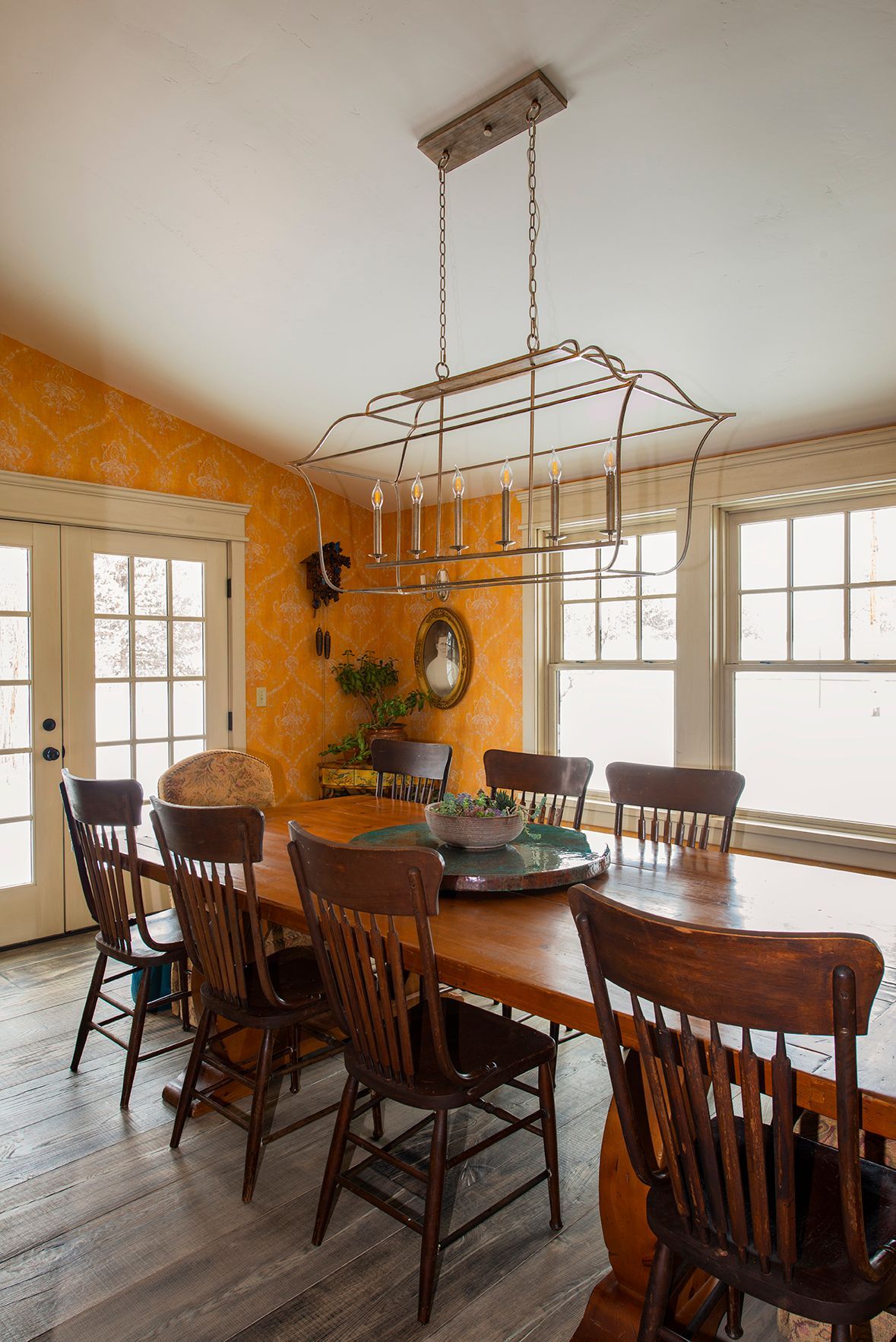 A dining room with a table and chairs and a chandelier hanging from the ceiling.