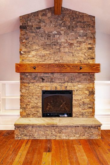 A stone fireplace with a wooden mantle in a living room