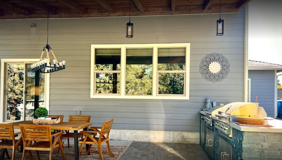 A patio with a table and chairs and a large window