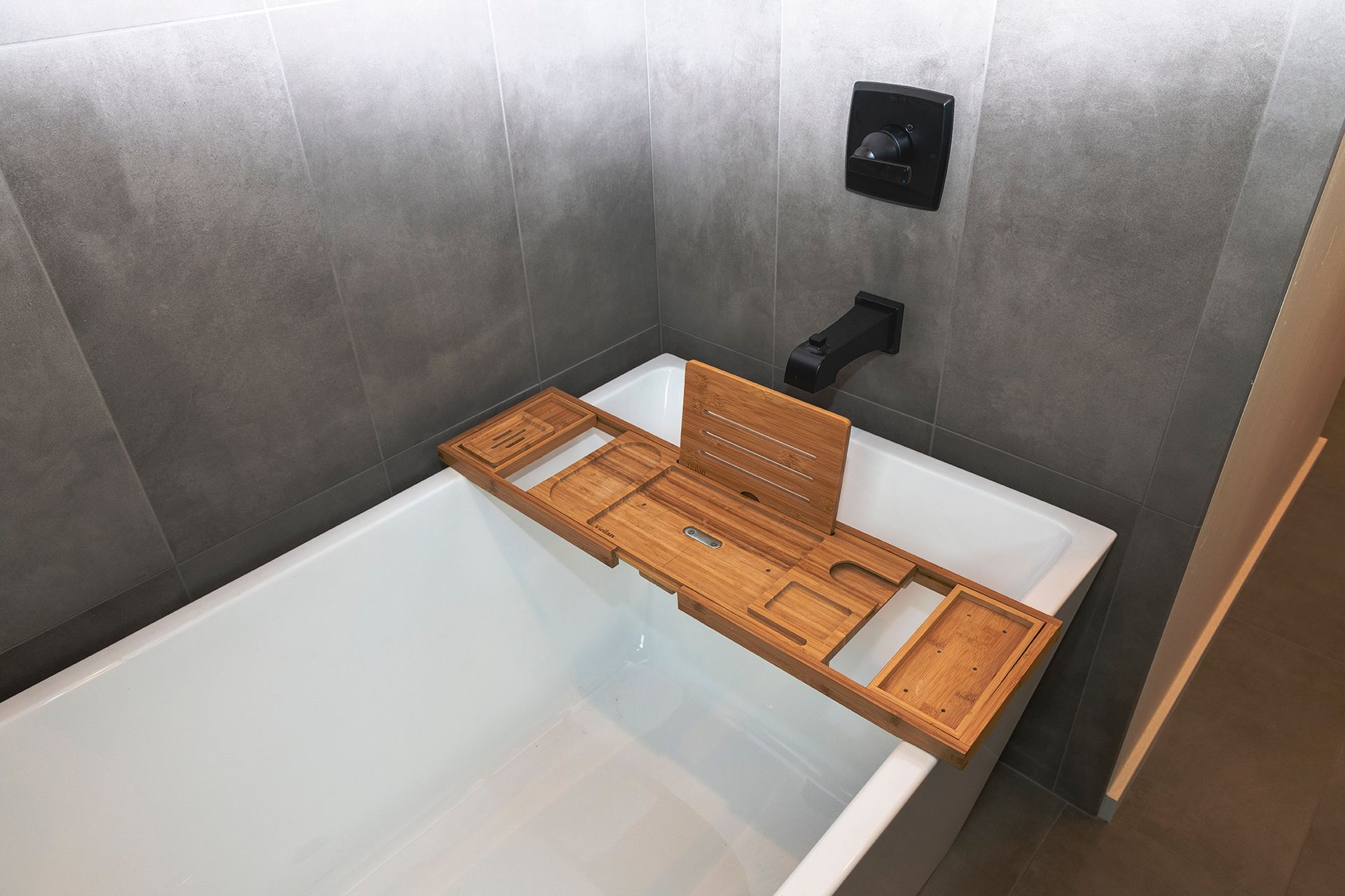 A bathtub with a wooden bathtub tray on top of it.