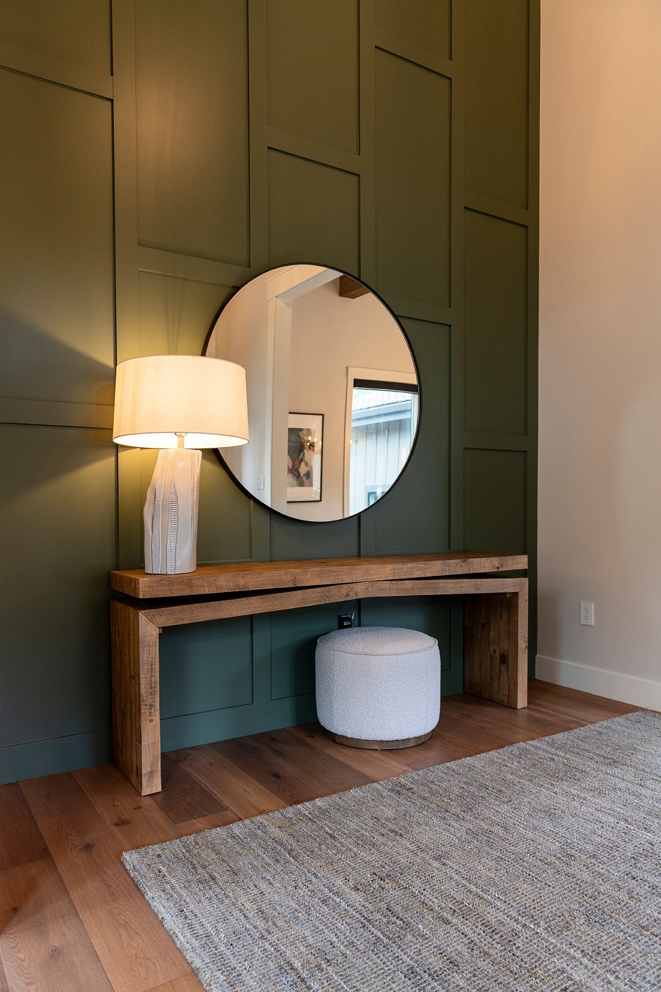 A room with a table , mirror , lamp and rug.