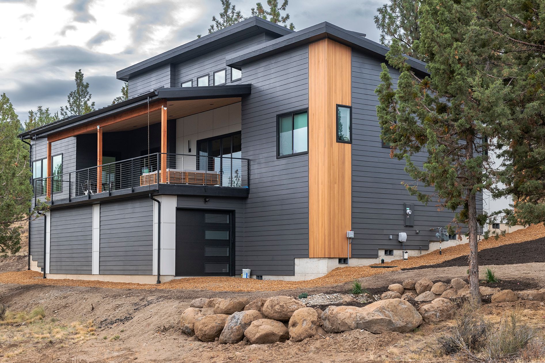 A large gray and wooden house is sitting on top of a dirt hill.