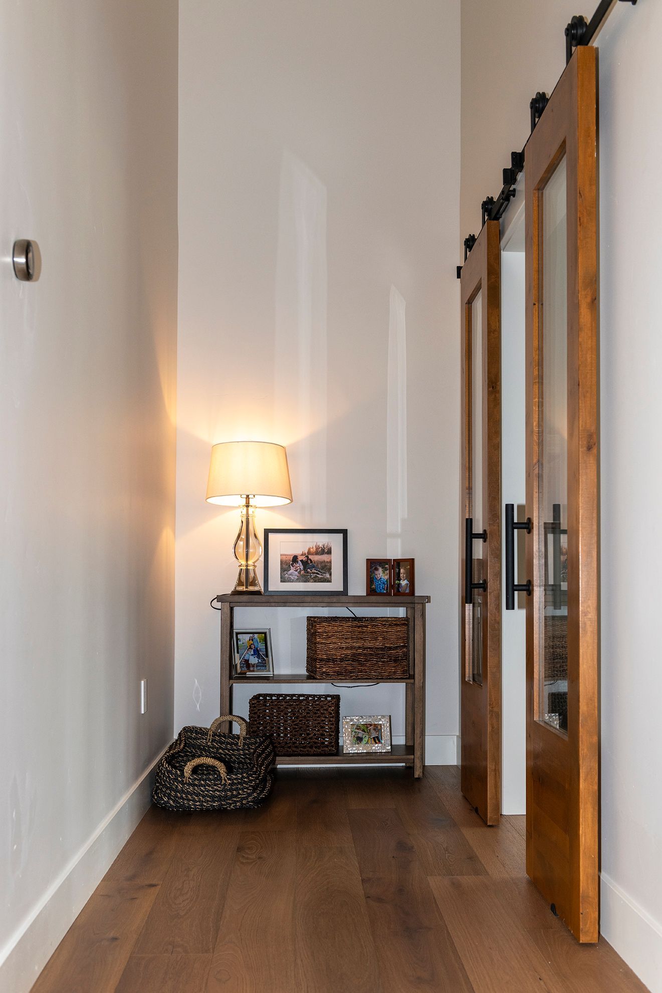A hallway with sliding barn doors and a table with pictures on it.