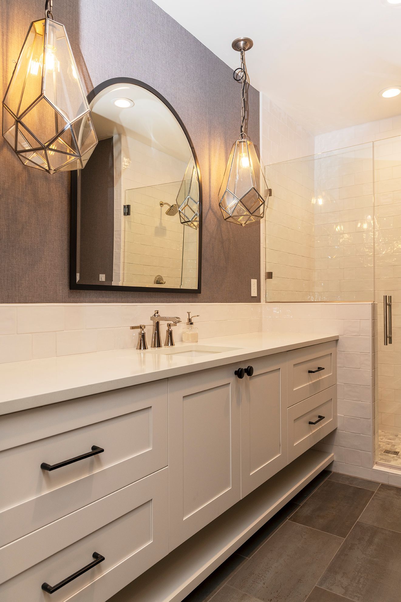 A bathroom with two sinks , a mirror , and a walk in shower.