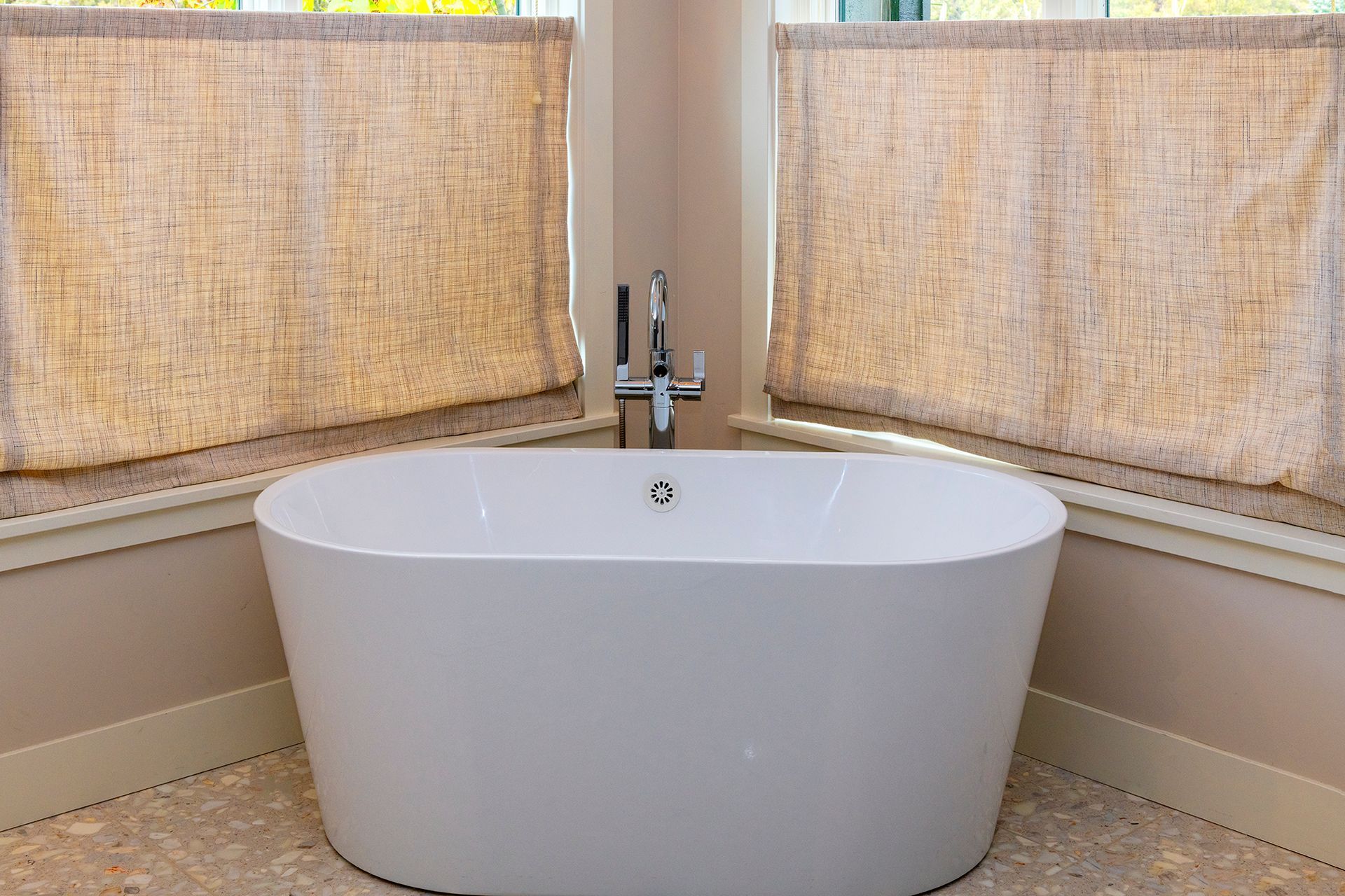A white bathtub is sitting in a bathroom next to a window.