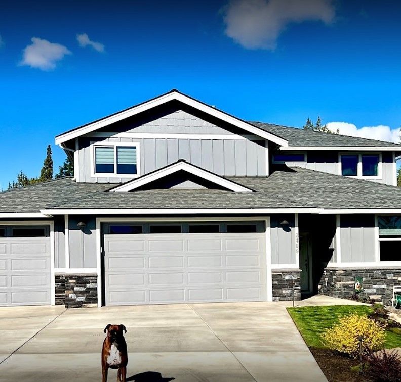A dog is standing in front of a large house